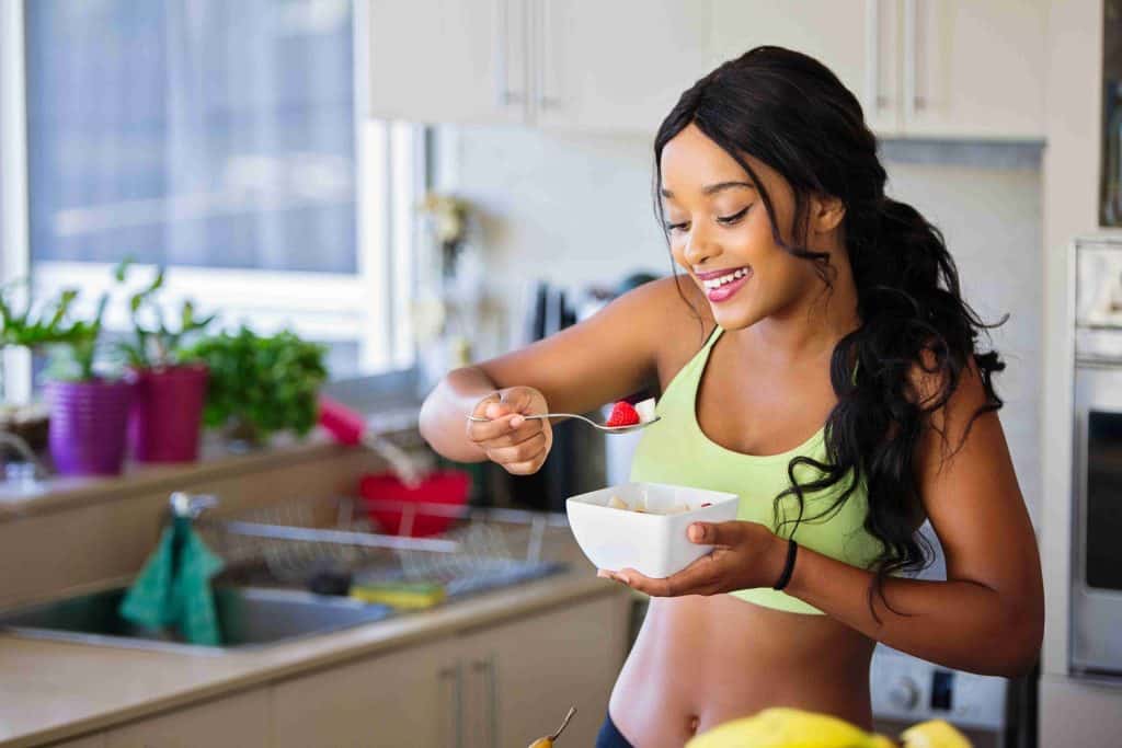 A woman eating a bowl of cereal in the kitchen.