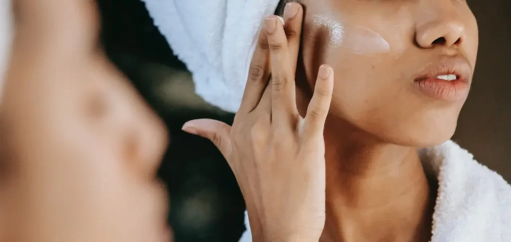 A woman with a towel on her face examining her post-surgery results.