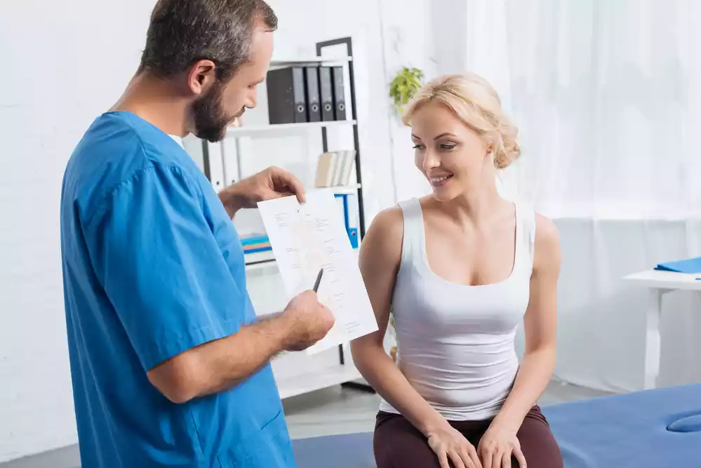 A man is discussing tummy tuck results with a woman in a doctor's office.