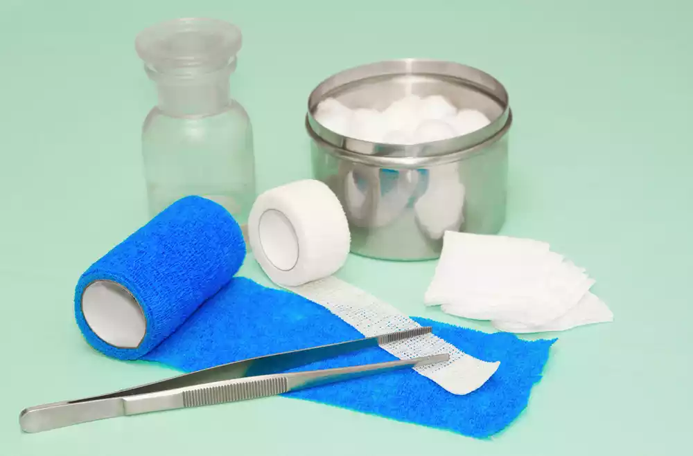 A medical kit with bandages and scissors on a green background.