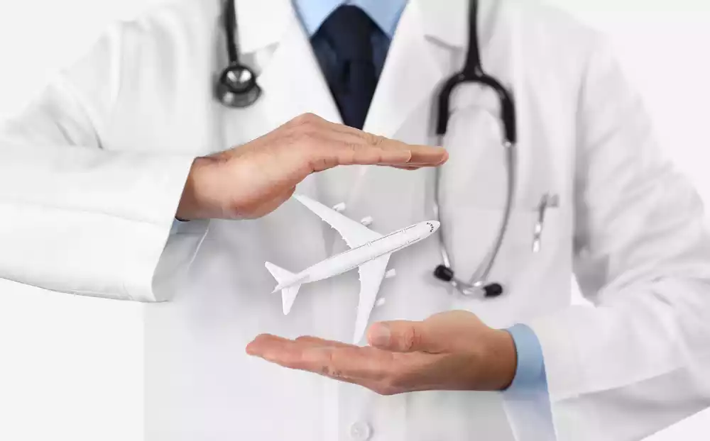 A doctor in a white coat with a stethoscope holds a model airplane between his hands, symbolizing healthcare and turismo médico en México.
